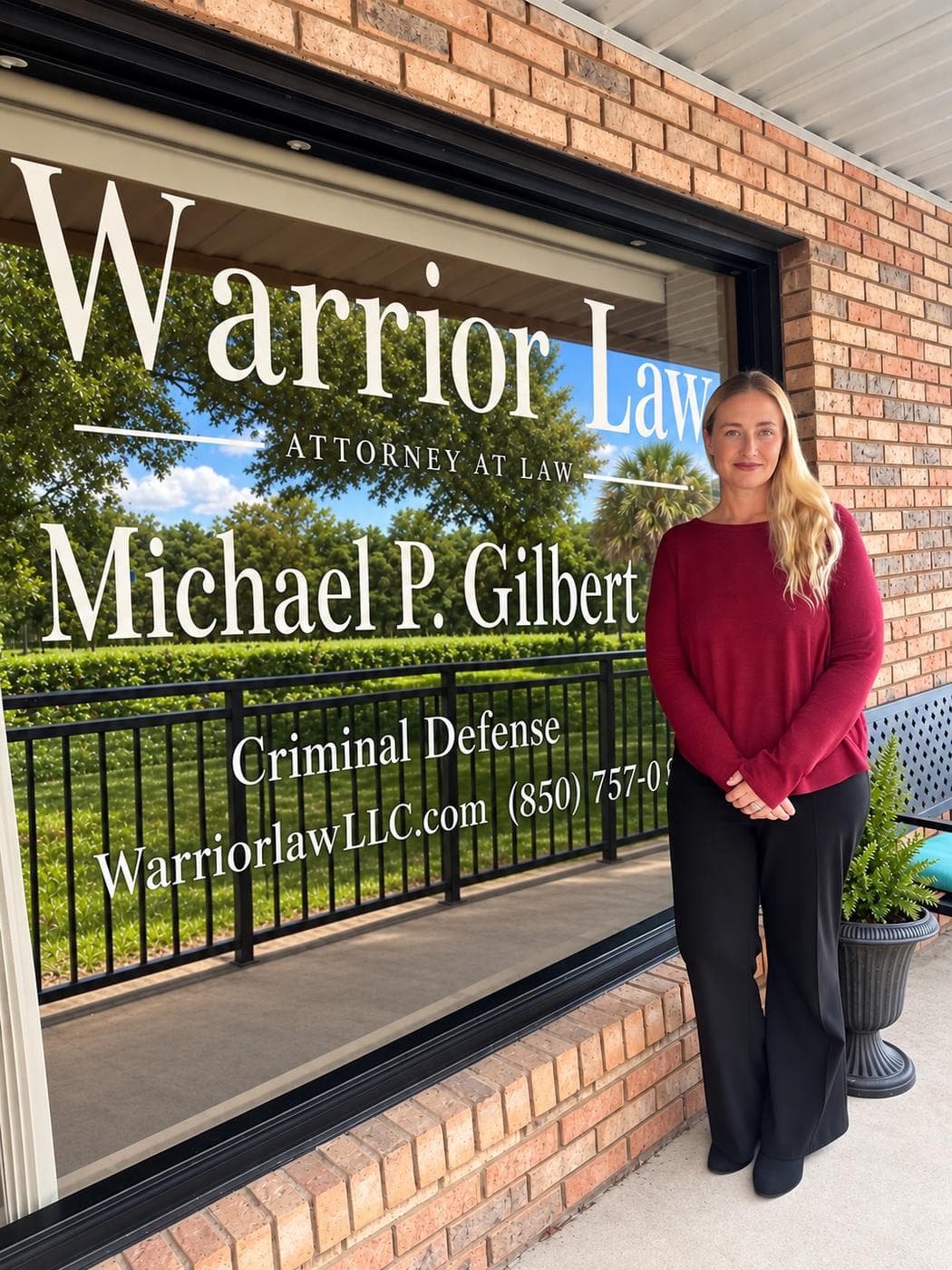 Melissa, in-house investigator at Warrior Law LLC, standing outside the firm's Crestview, Florida office in front of the branded storefront window