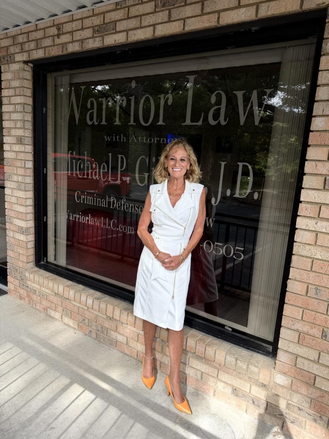 Renee, paralegal at Warrior Law LLC, standing outside the firm's Crestview, Florida office in front of the branded storefront